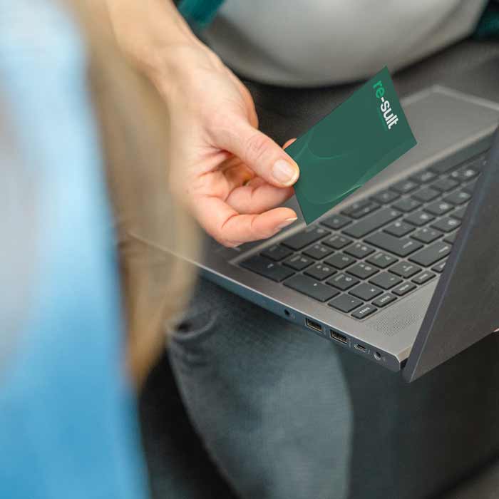 Eine Person überreicht die grüne re-sult-Visitenkarte an eine Geschäftspartnerin.
