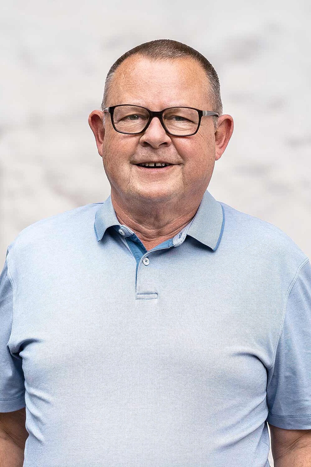 Florian Ilmberger trägt ein helles Poloshirt und steht vor einem hellgrauen Hintergrund.
